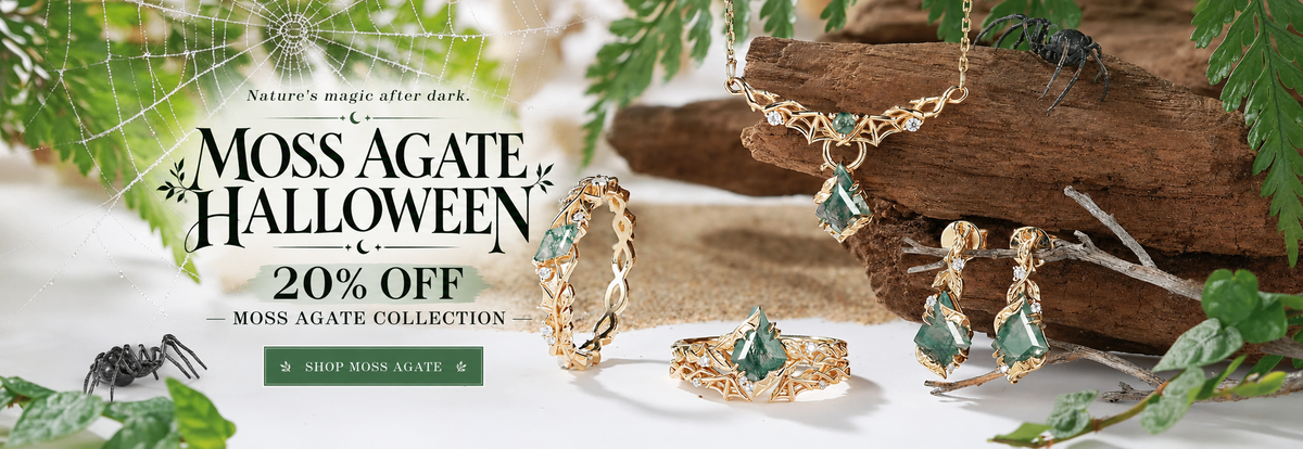 Moss Agate Collection Halloween promotional banner featuring gold jewelry with green gemstones, including a necklace, earrings, and rings, styled with autumn leaves, a spider, and a piece of wood. Text on the left reads 'MOSS AGATE HALLOWEEN 20% OFF' with a 'SHOP MOSS AGATE' button.